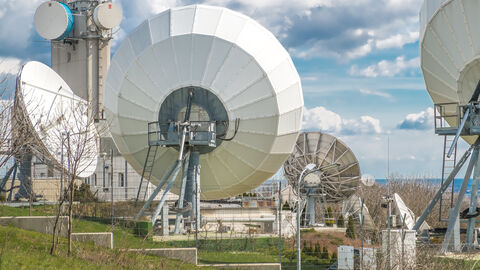 Auf dem Bild sieht man mehrere große weiße Satellitenschüsseln und andere Kommunikationstechnik