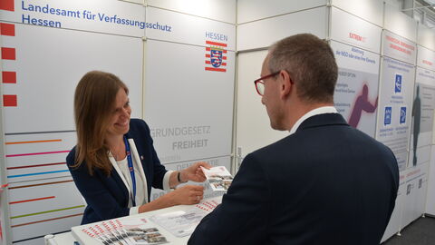 Eine Mitarbeiterin des LfV Hessen spricht auf dem Hessentag mit einem Standbesucher