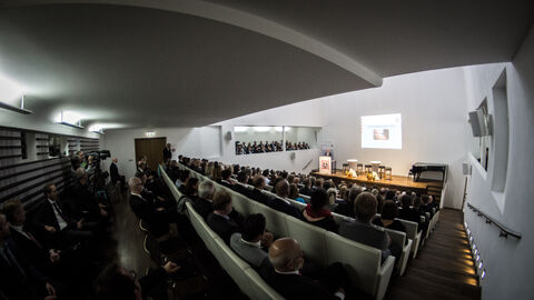 Blick in den Saal des Museums Wiesbaden. Man sieht das Publikum der Verastaltung vor der Bühne sitzen.