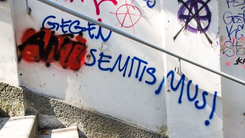 Graffiti-Schriftzug "Gegen Antisemitismus" auf einer Hauswand. Der Wortteil "Anti" ist mit roter Farbe besprüht.