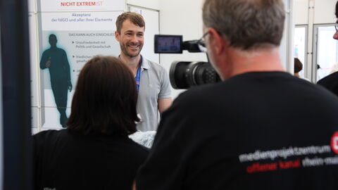 Der Leiter des Kompetenzzentrum Rechtsextremismus am LfV Hessen, Sven Daniel, gibt am Stand des LfV Hessen auf dem Hessentag in Pfungstadt ein Statement vor einem Kamerateam ab.