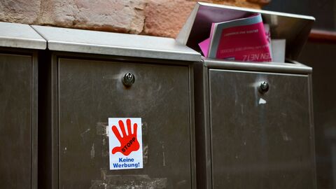 Bild von zwei Briefkästen. Auf einem ist ein Aufkleber mit der Aufschrift "Keine Werbung" angebracht. In dem anderen steckt eine Broschüre.